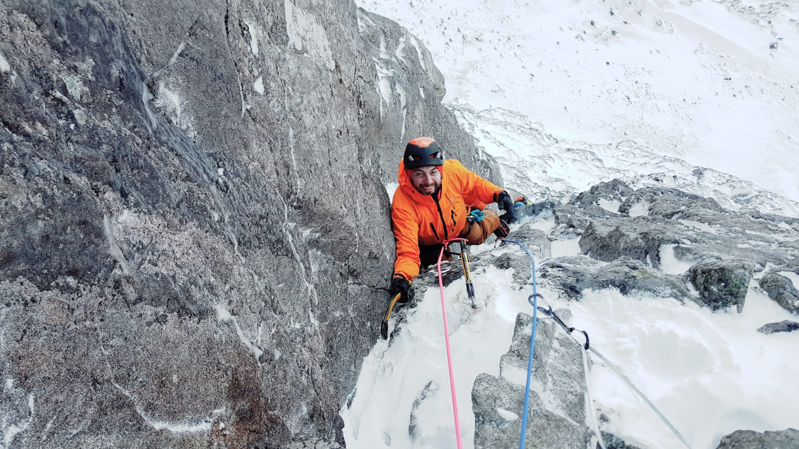 A man climbs using ice axes in the mountains of Scotland.