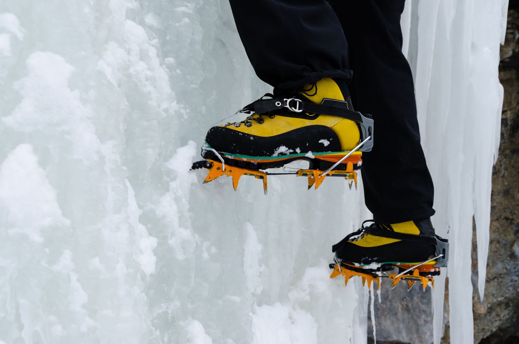 A close up of crampons driving into a wall of ice.