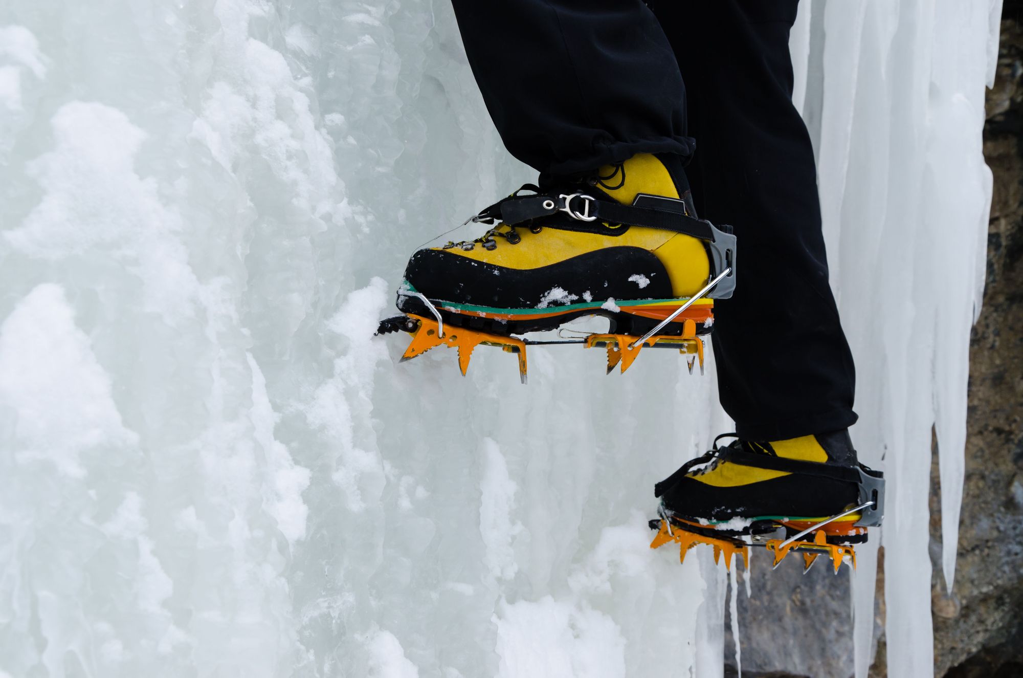 A close up of crampons driving into a wall of ice.