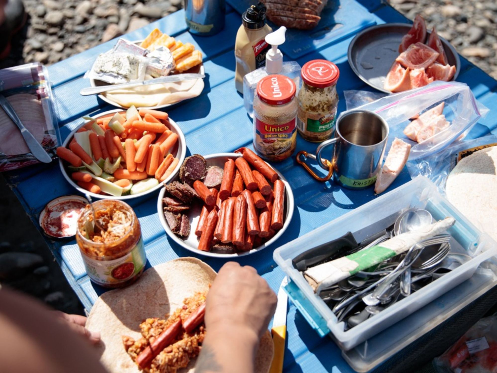 A camping meal of sausages, peanut butter, crudites and cheese.