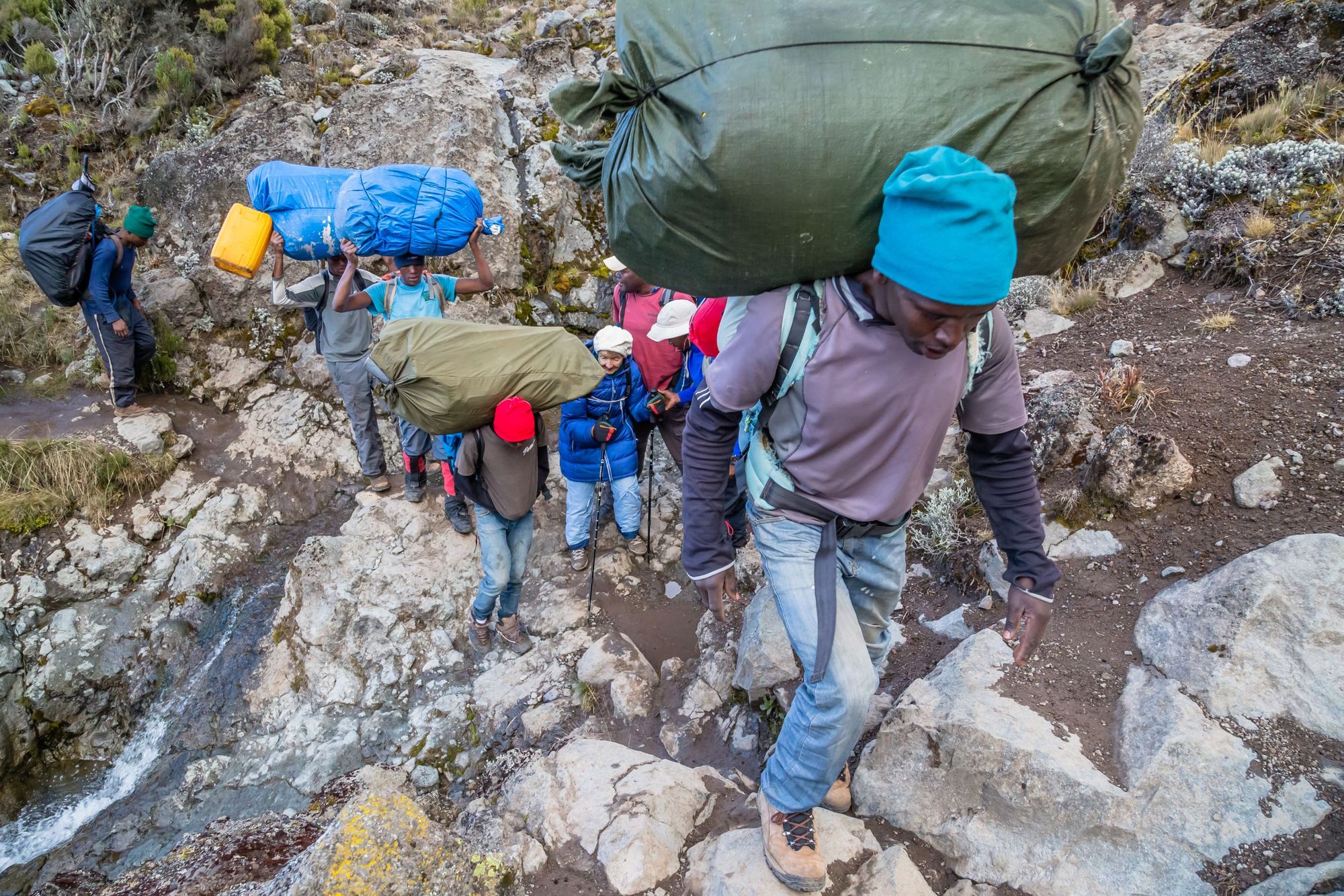Porters burdened with heavy packs as they climb Mount Kilimanjaro.