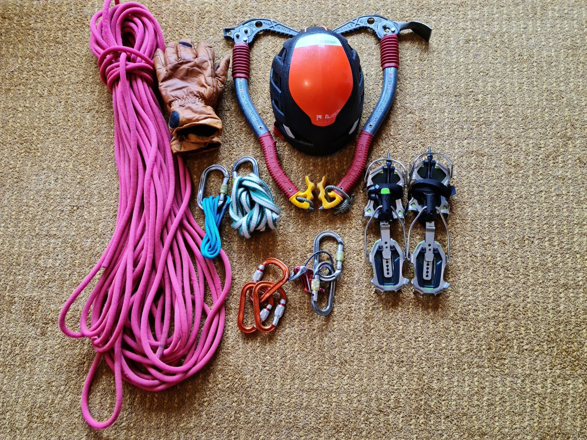 Winter climbing equipment including rope, gloves, carabiners, crampons, helmet and a pair of technical axes.