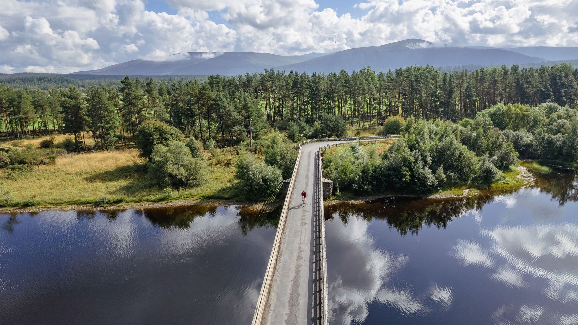 Stitz rides over a bridge in the national park, with the shadow of the mountains behind. Photo: Markus Stitz
