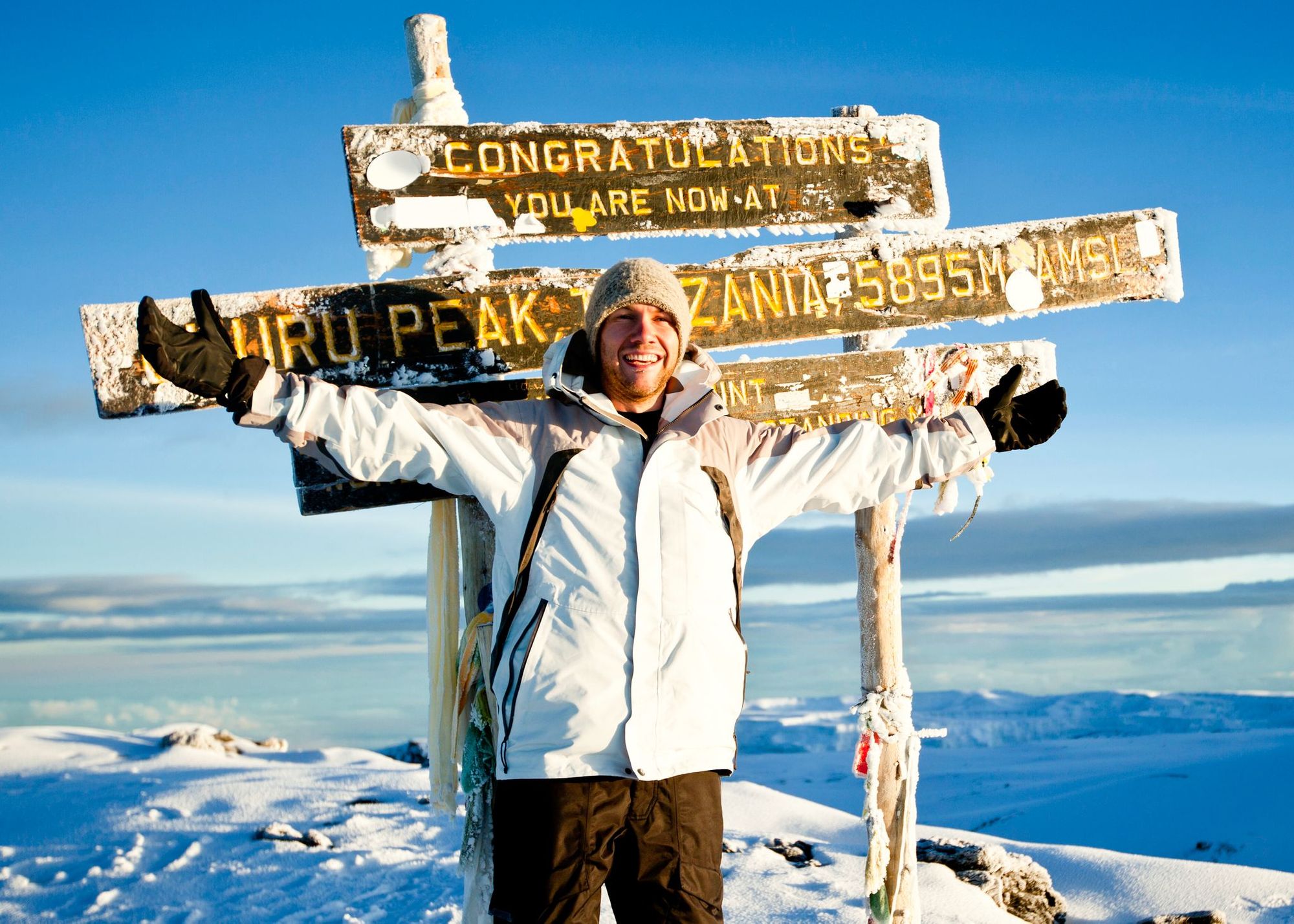 A man poses in front of the 'congratulations' sign at the top of Mount Kilimanjaro, Tanzania