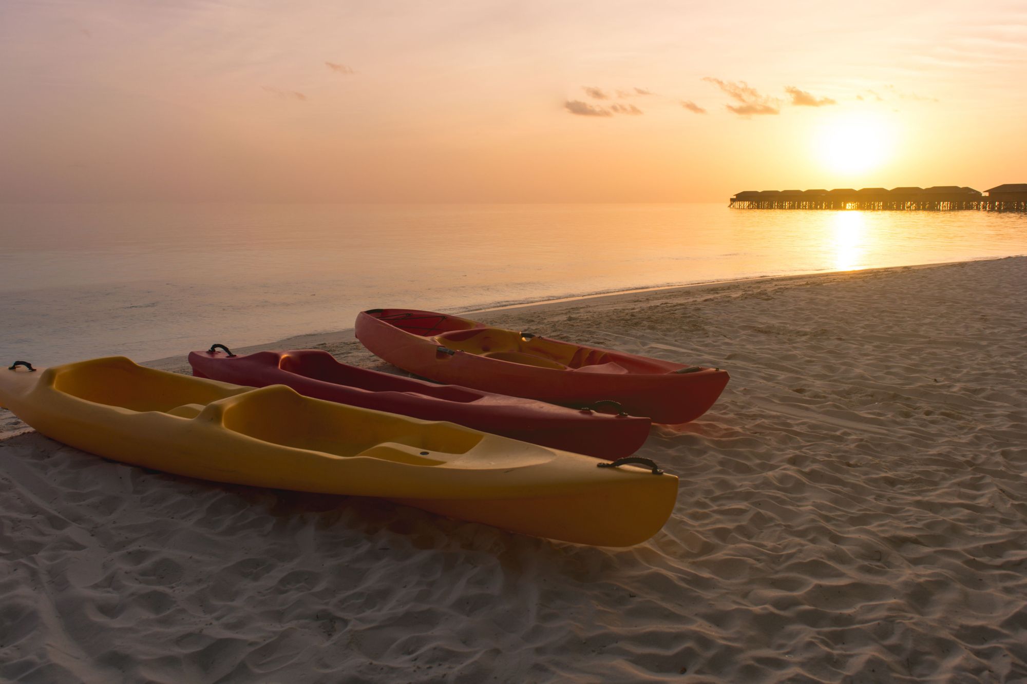 Kayaks pulled ashore in the Maldives, at sunset.