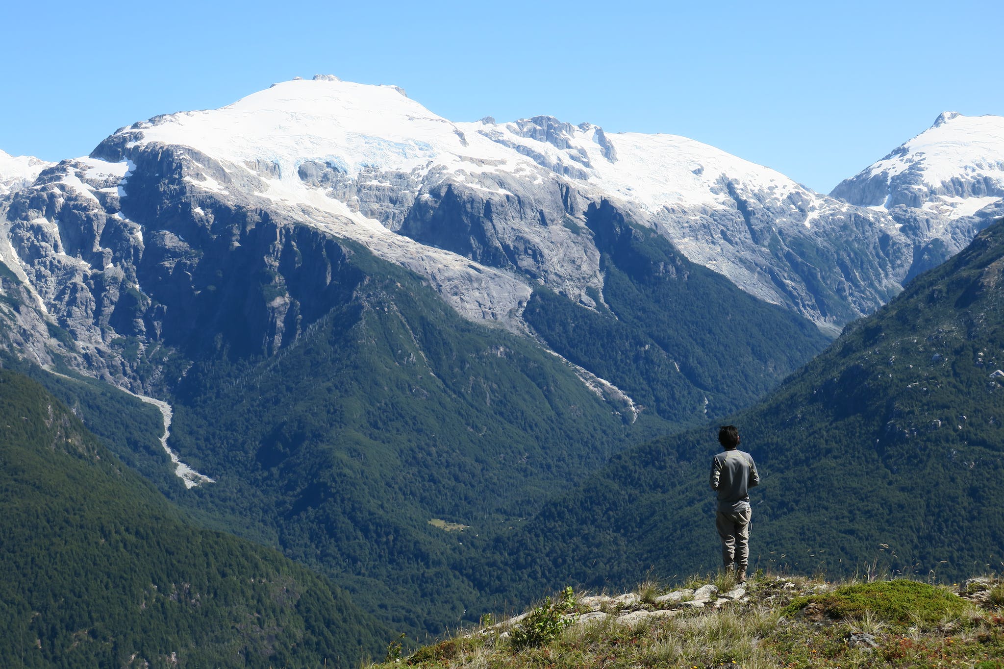 A man looks out at the forested mountains of the Ventisquero Valley, Chilean Patagonia