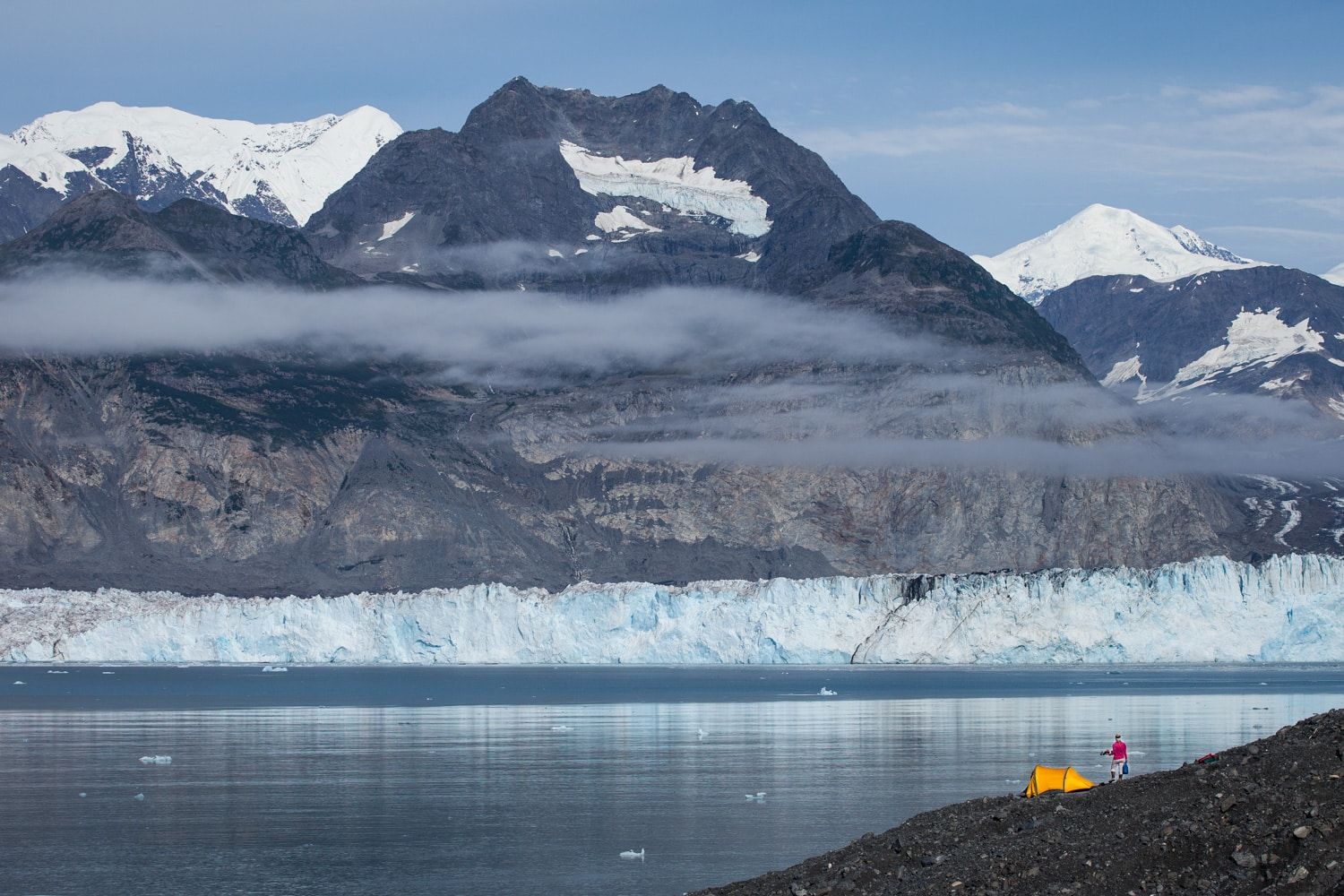 A yellow tent erected on the shores of a glacial lake, Alaska.