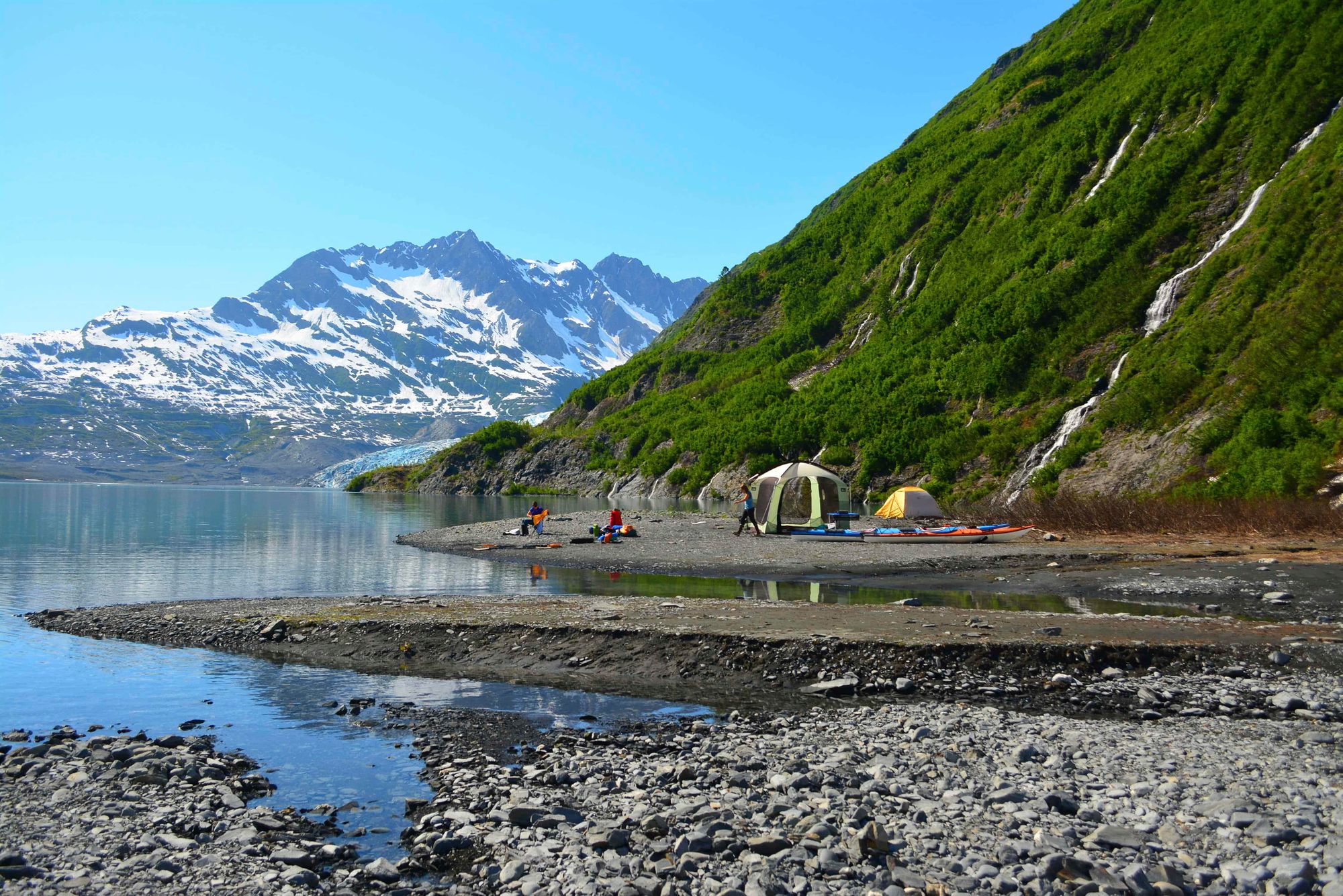 A wild campsite on a sand bar in Alaska, with a glacier behind