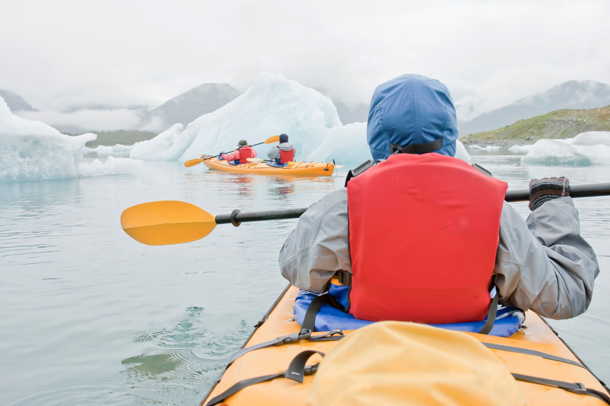 Three kayakers in Alaska.