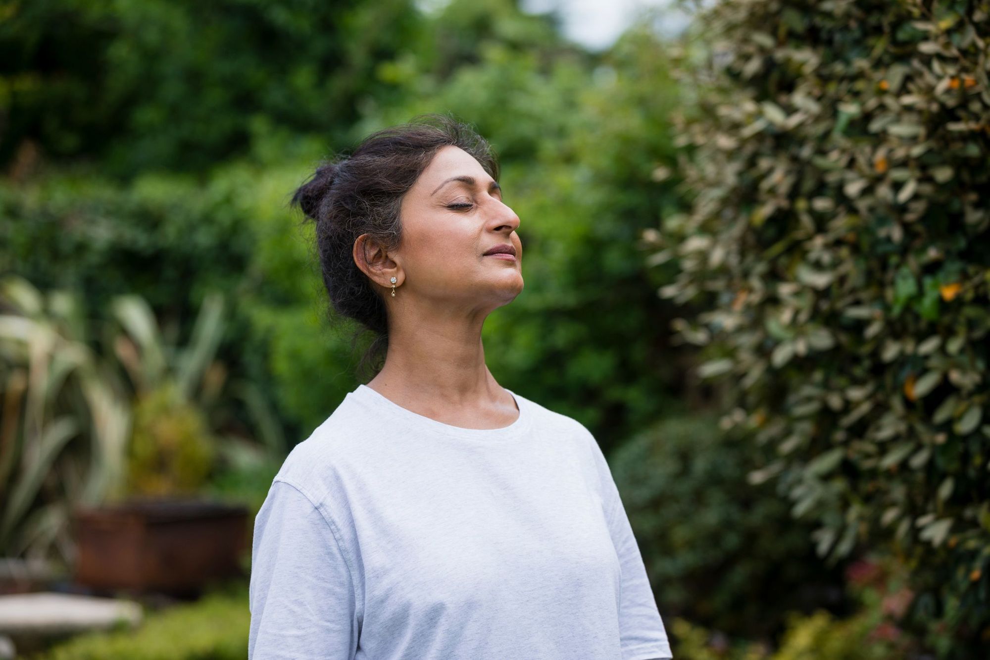 A woman with her eyes closed, relaxing in nature.