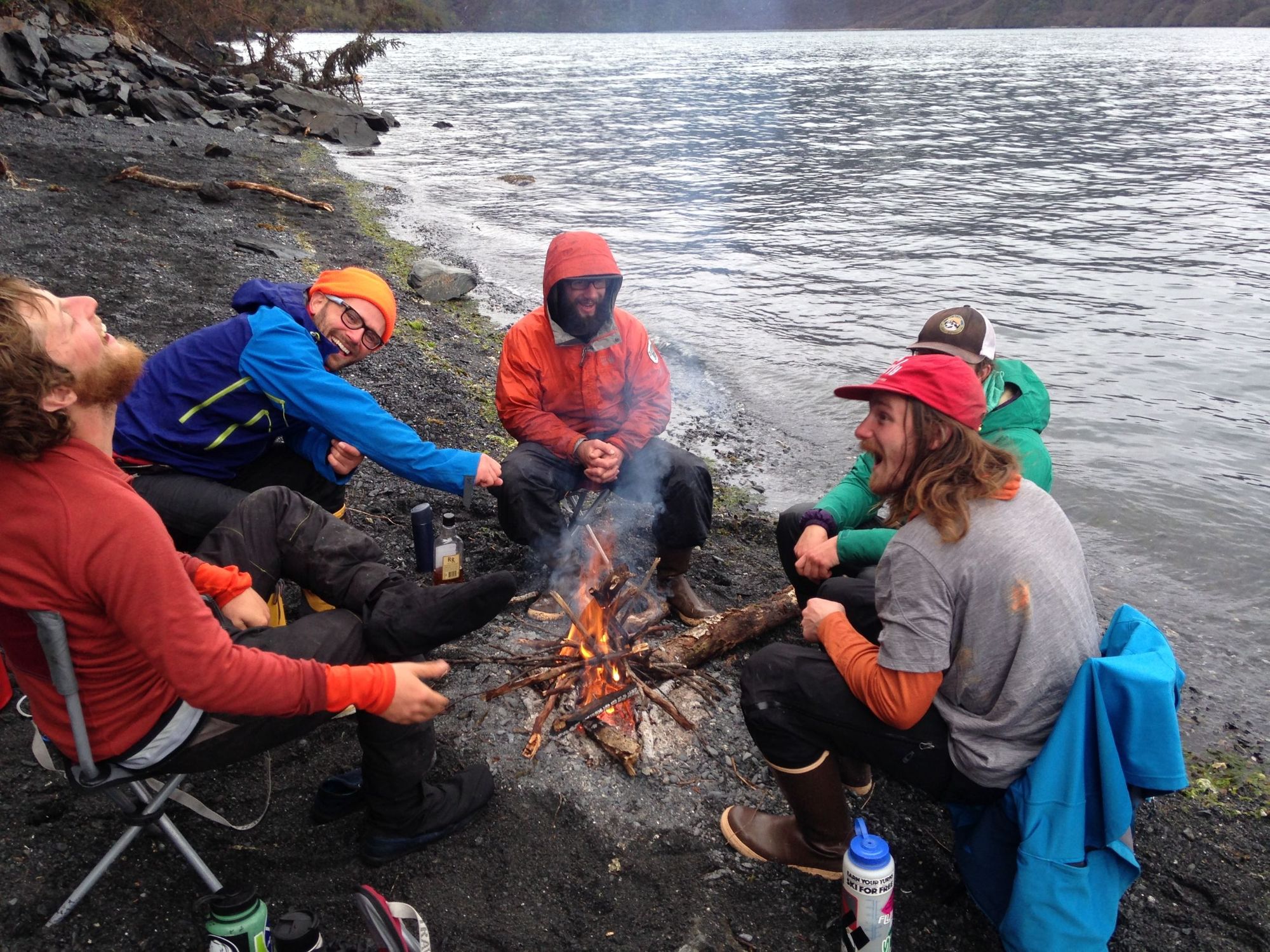 A group of campers round the fire, by the shores of a lake in Alaska.