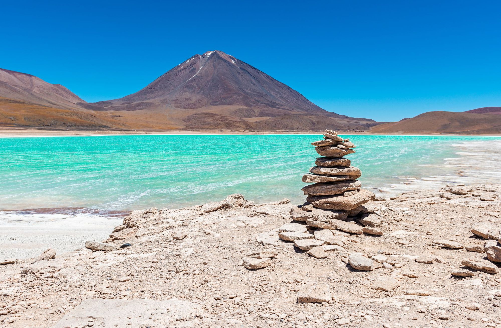The vivid blue waters of Lagnuas Verde, which lies just below Volcan Licancabur on the Altiplano Traverse, a long distance hike in South America. Photo: Getty