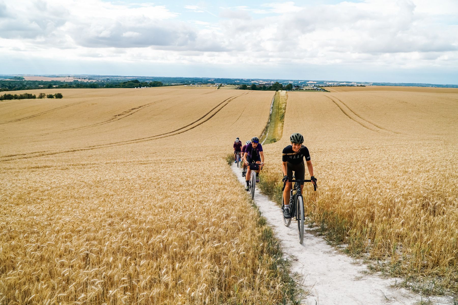 Cyclists biking through a wheat field, part of the Ridgeway cycling trail. Photo: Wild Cycles.
