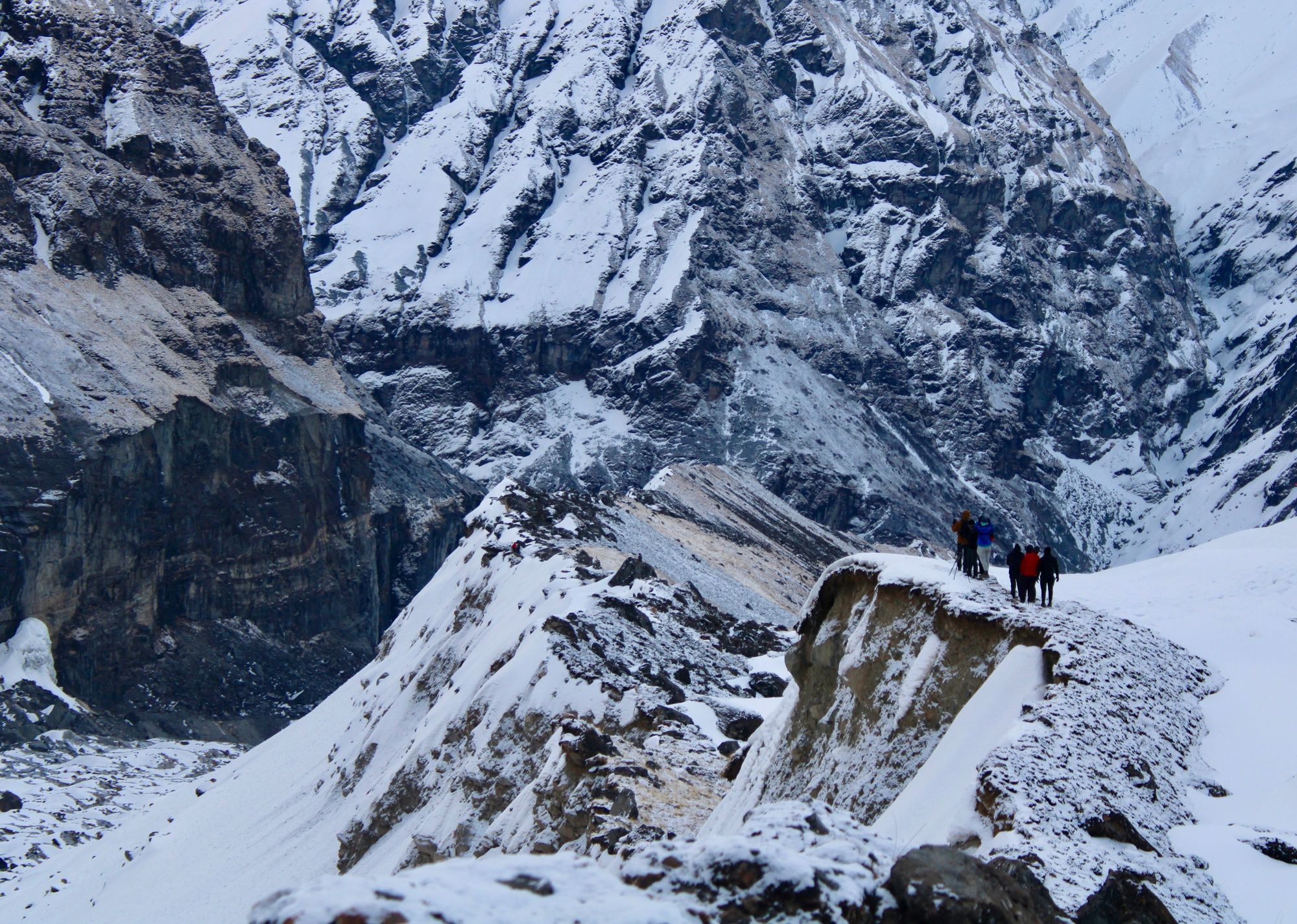 A small group of people photographing the majestic, snowy Himalayan mountains from Annapurna Base Camp, Nepal.