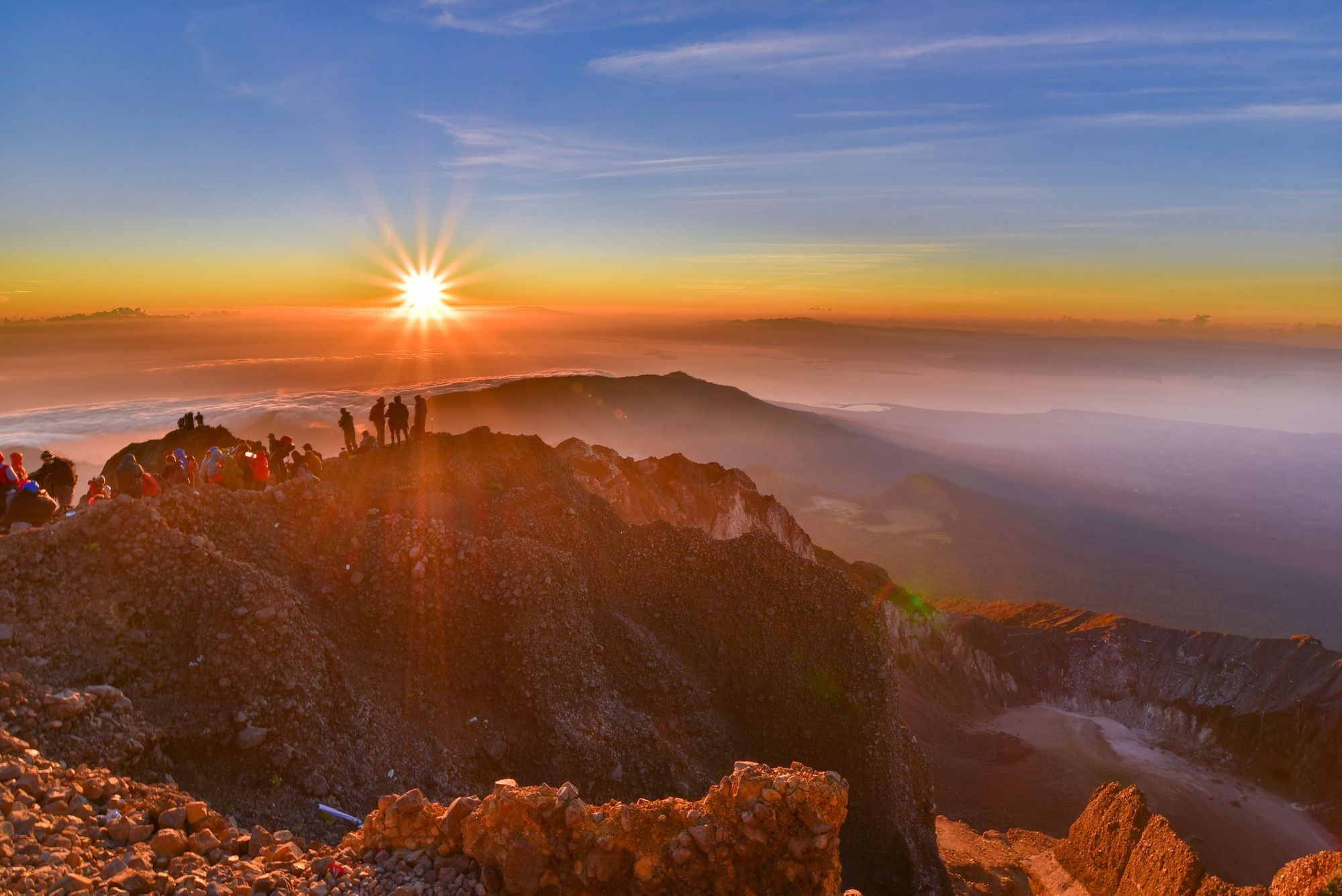 Climbers watch sunrise on the summit of Mount Rinjani, Indonesia