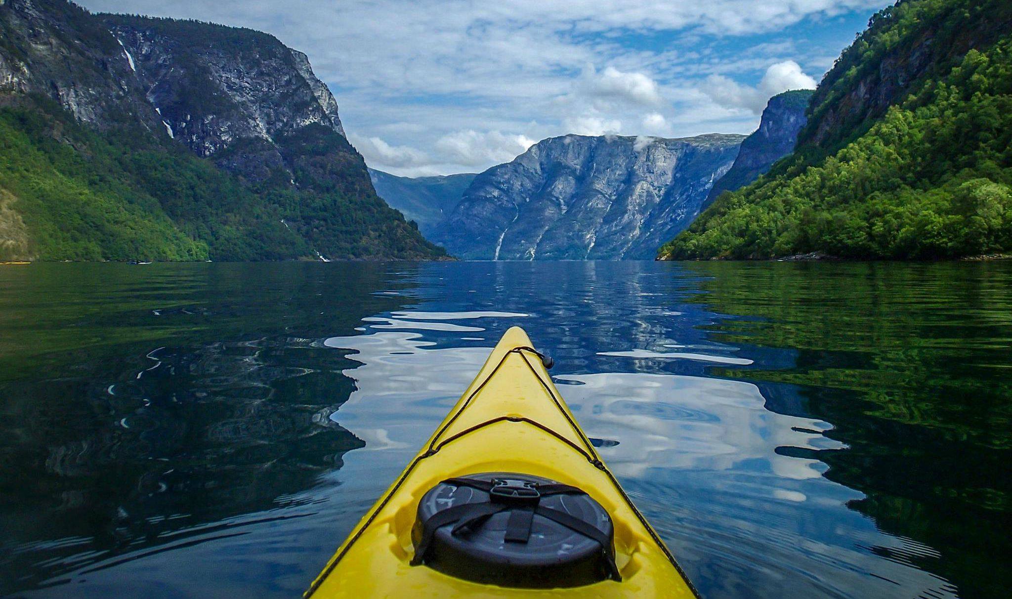 The front of a kayak as someone paddles down the Nærøyfjord, Norway