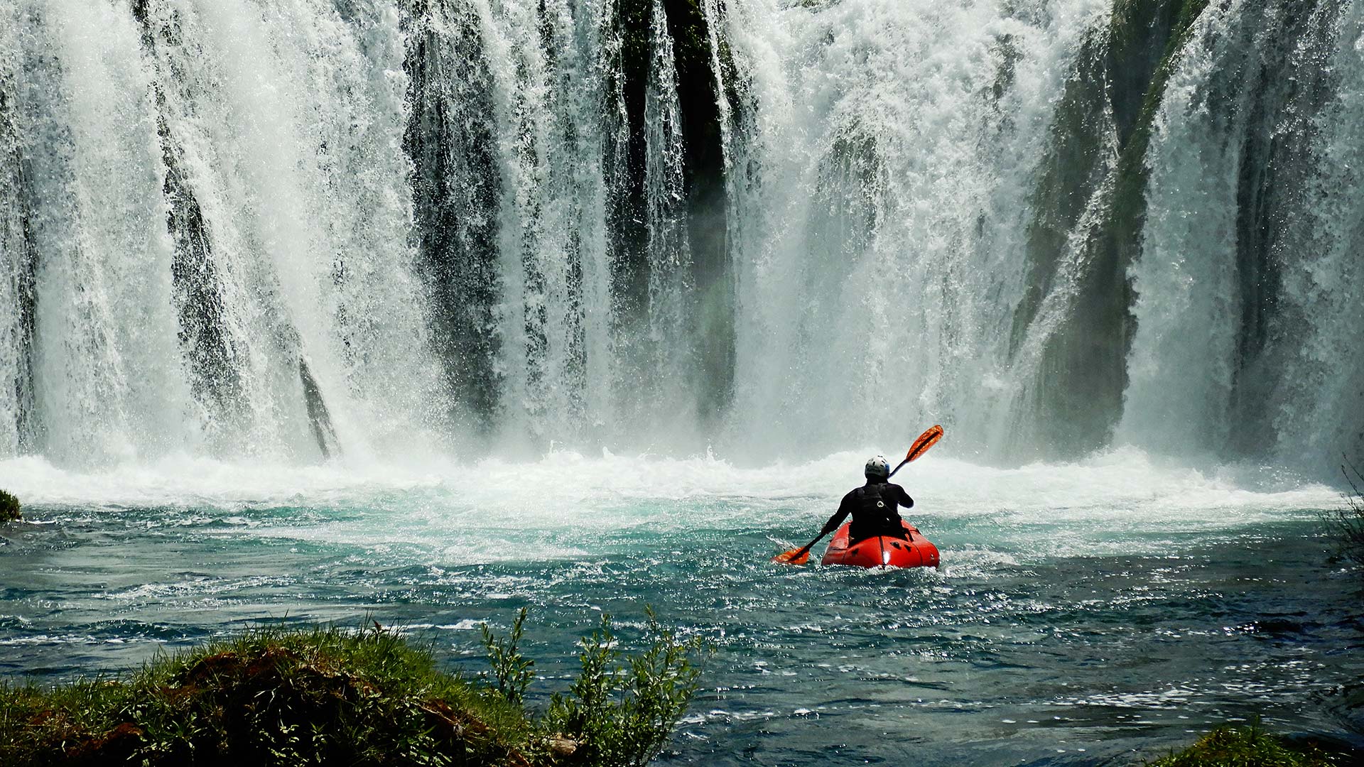 A man rafting in Croatia, in front of a waterfall