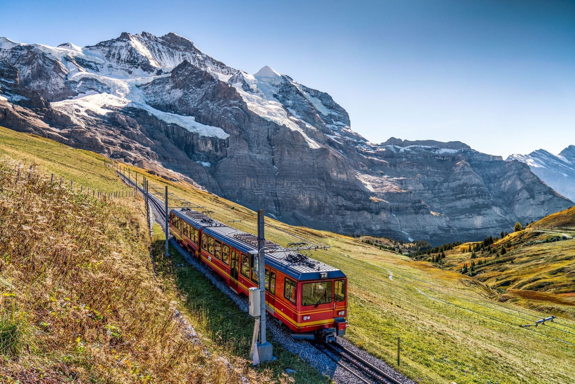 The red train running on the Jungfrau railway with a background view of Jungfrau. Photo: Getty