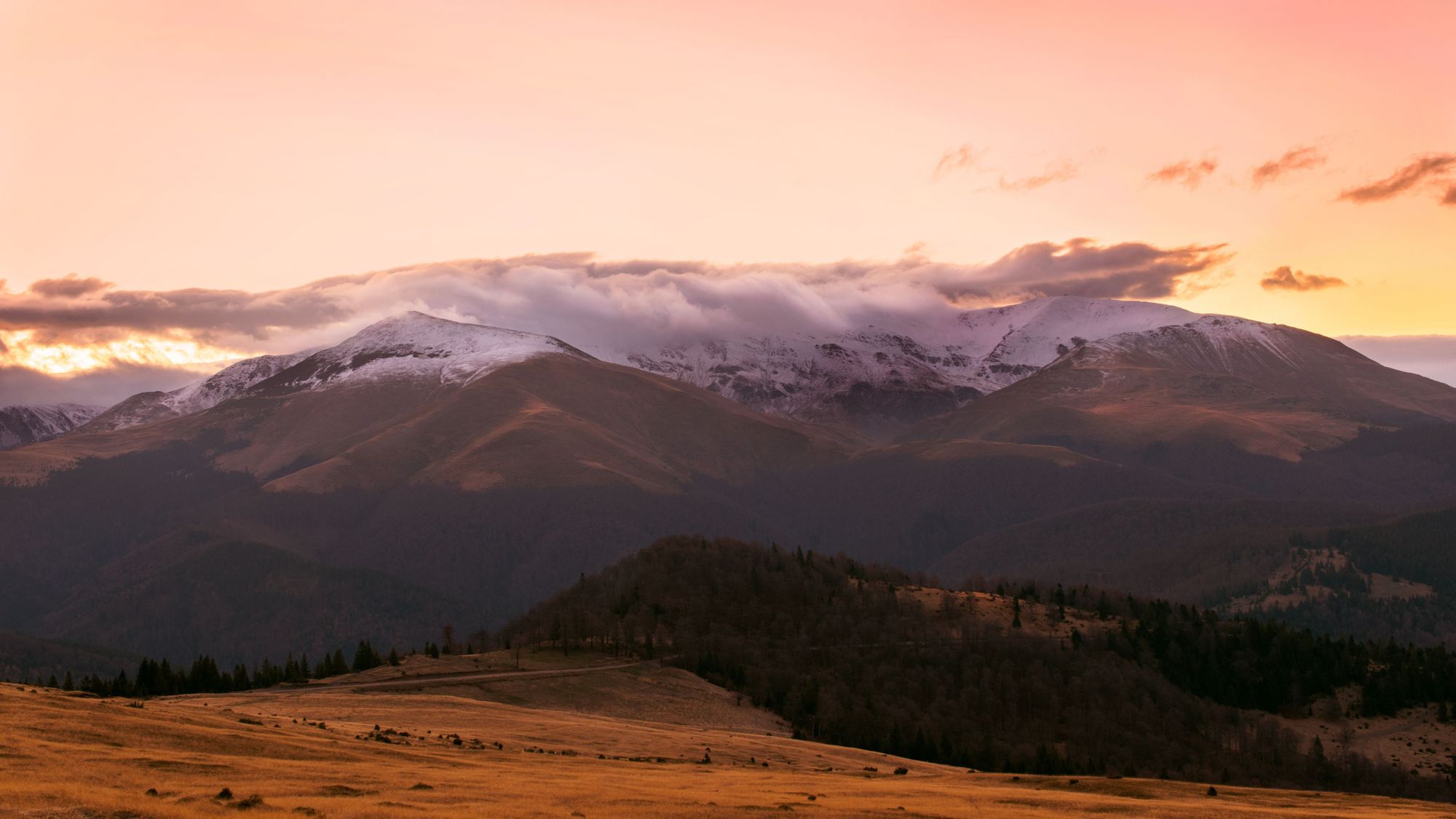 Clouds descend over the Tarcu Mountains of Romania as the sun sets. Photo: Getty
