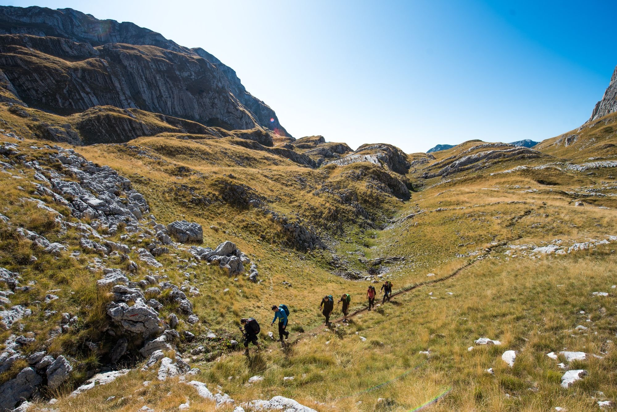 A group of hikers spread out in Montenegro, on a scenic mountain pass