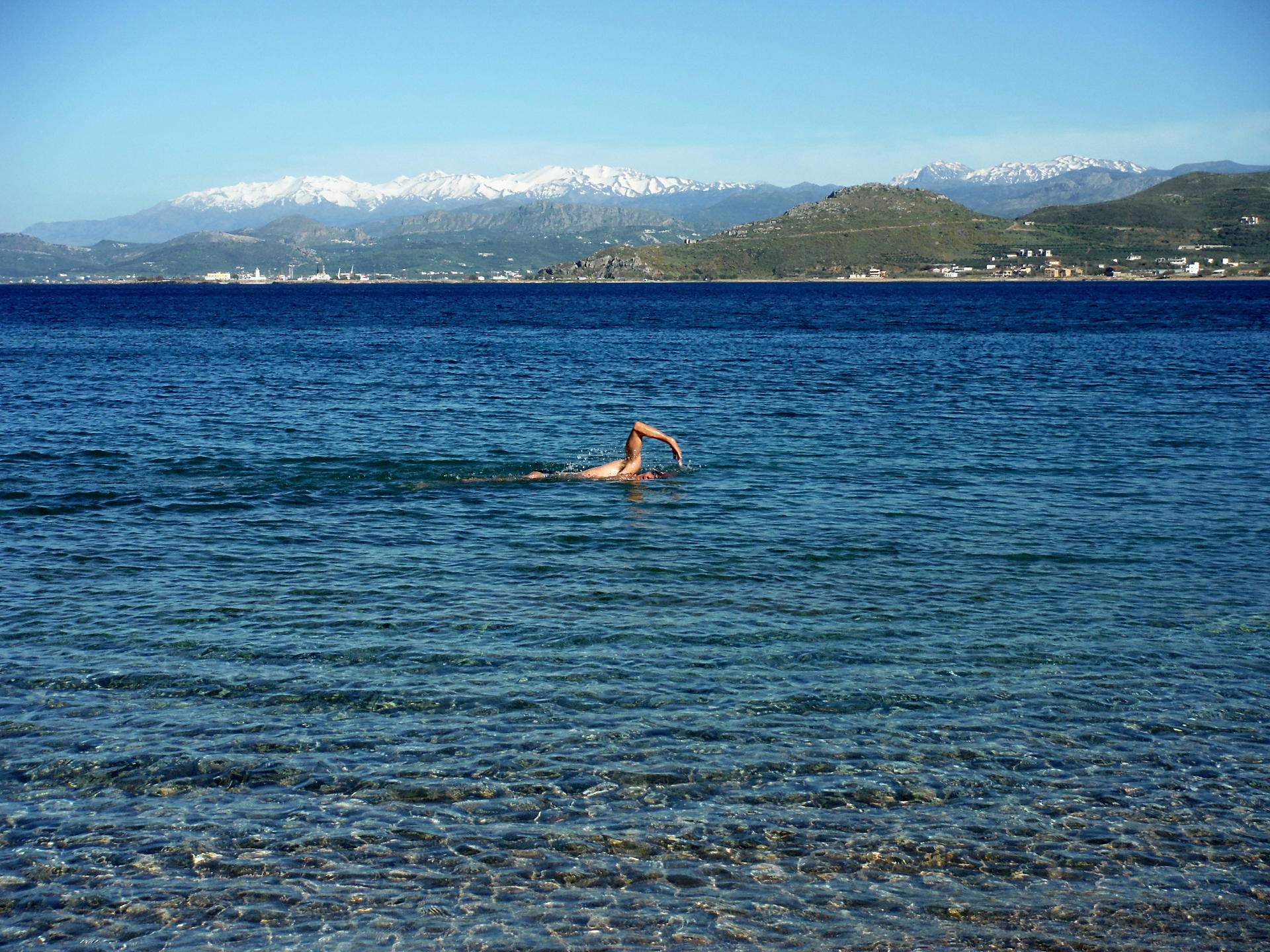 A man swims in the sea on a beach in Crete.