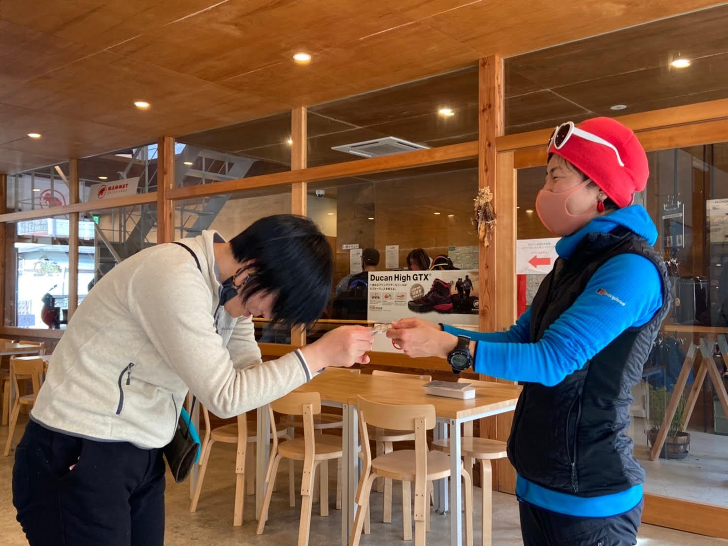 A Japanese guide presents her client with a certificate of achievement at the end of a hike.