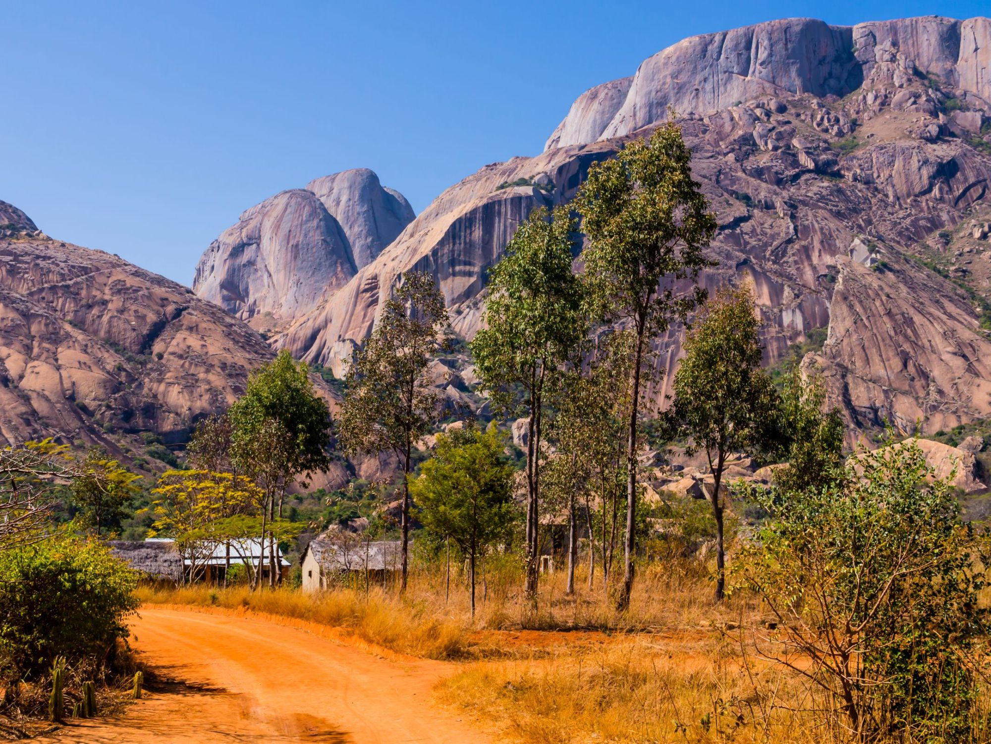 The granite mountains of Anja community reserve rise up behind the houses and trees. Photo: Getty