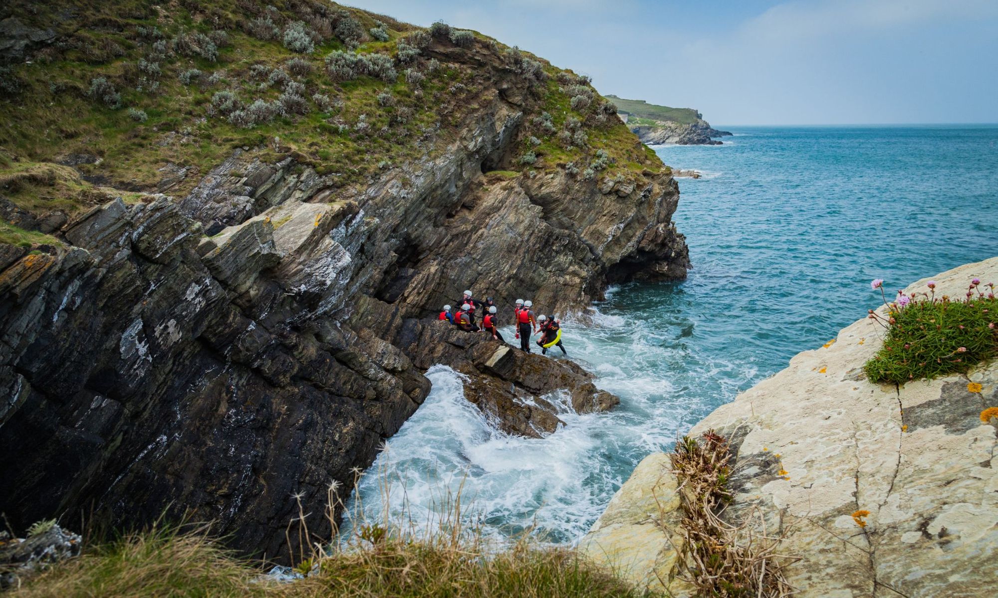 A group of people coasteering around the North Cornish coast, near Newquay.