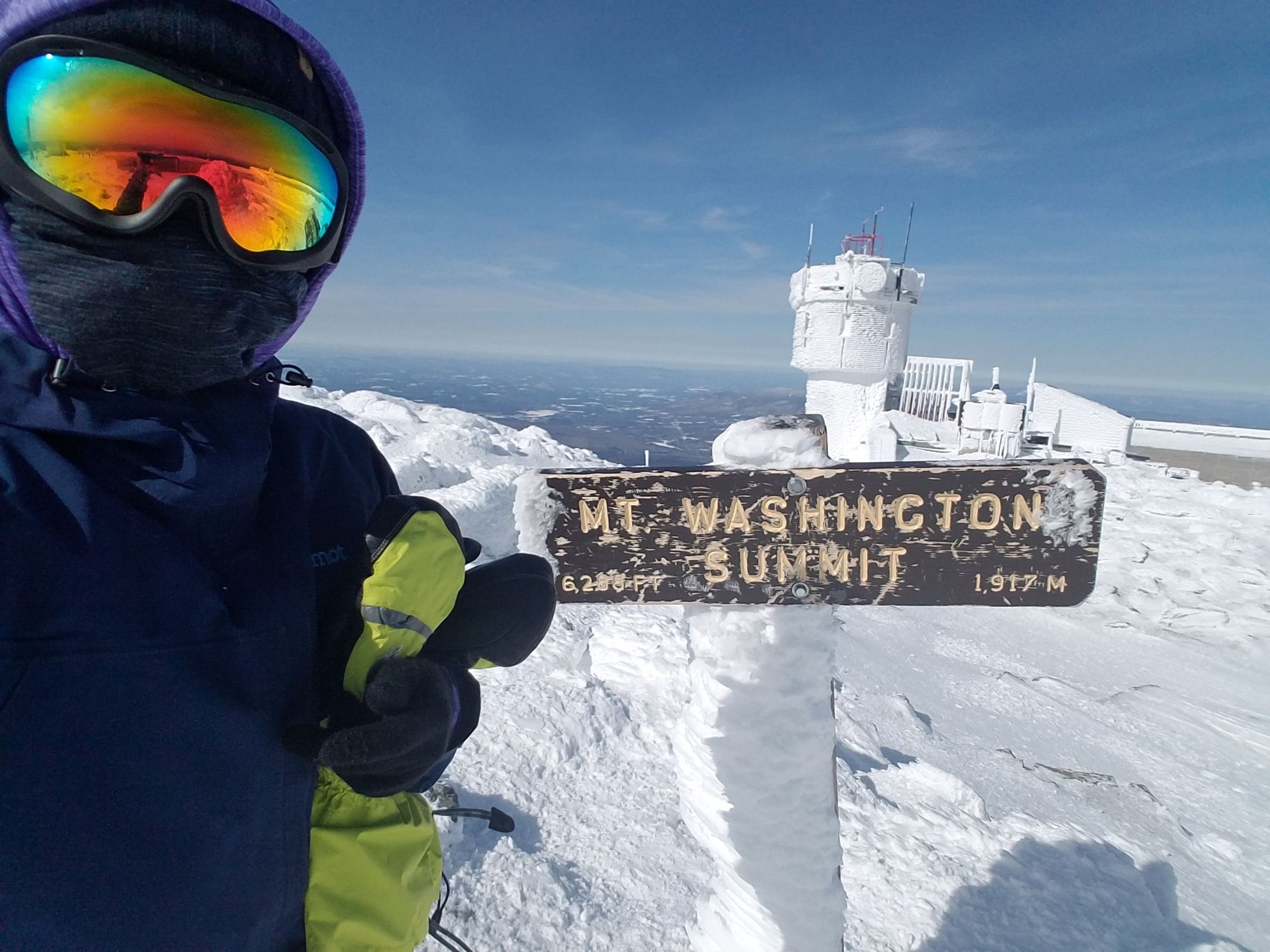 A woman poses on the summit of Mount Washington.