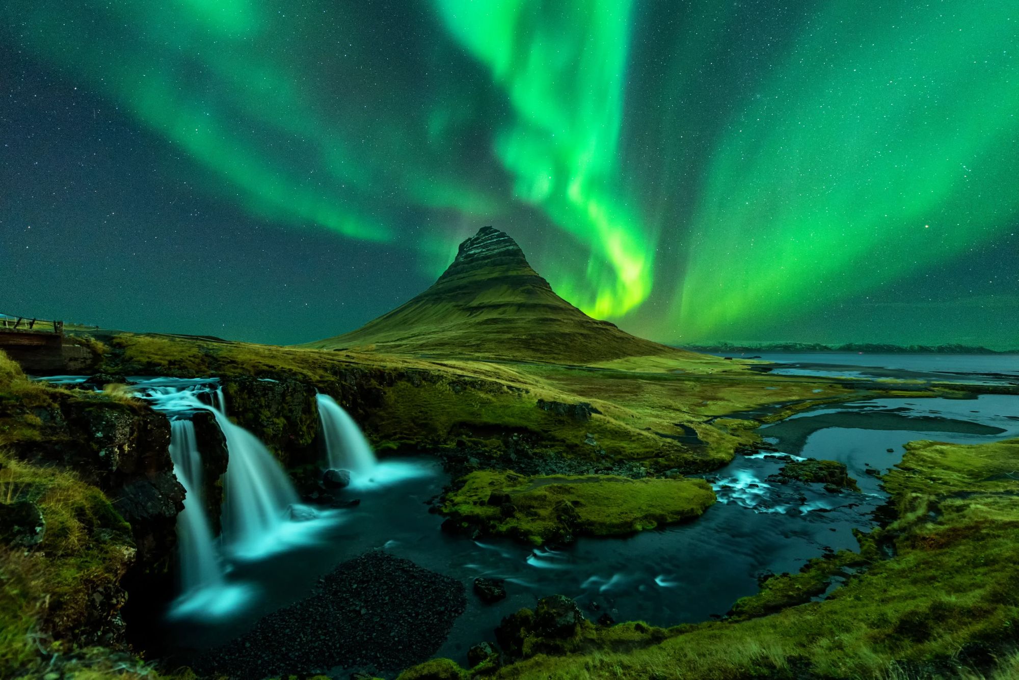 The northern lights shine over Mount Kirkjufell and the famous kirkjufellfoss waterfall in Iceland. Photo: Getty