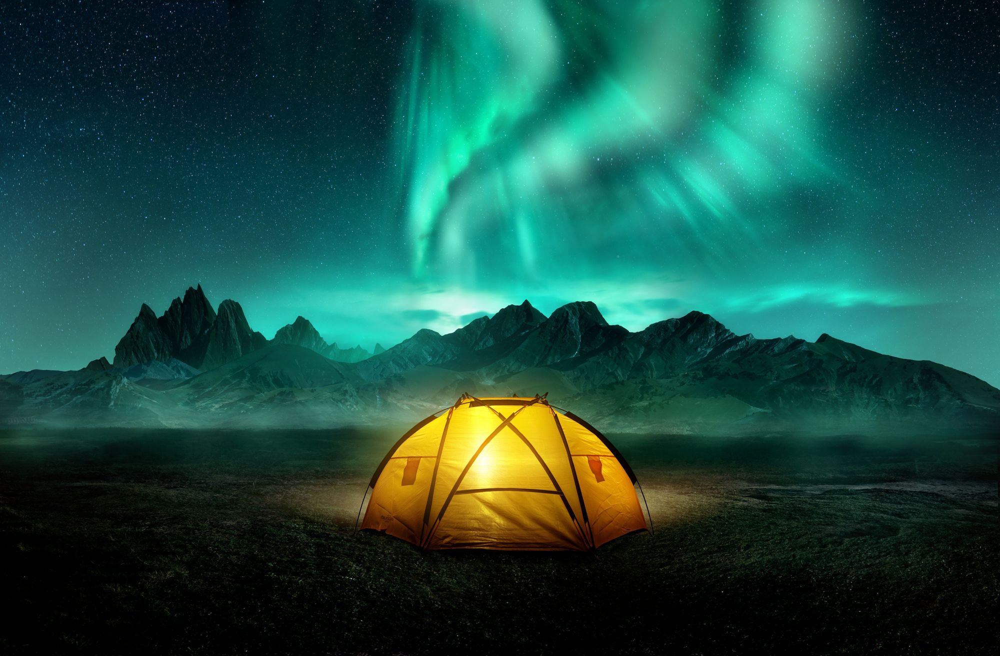 A tent set up beneath the mountains of Svalbard on a cold winter night. Photo: Getty