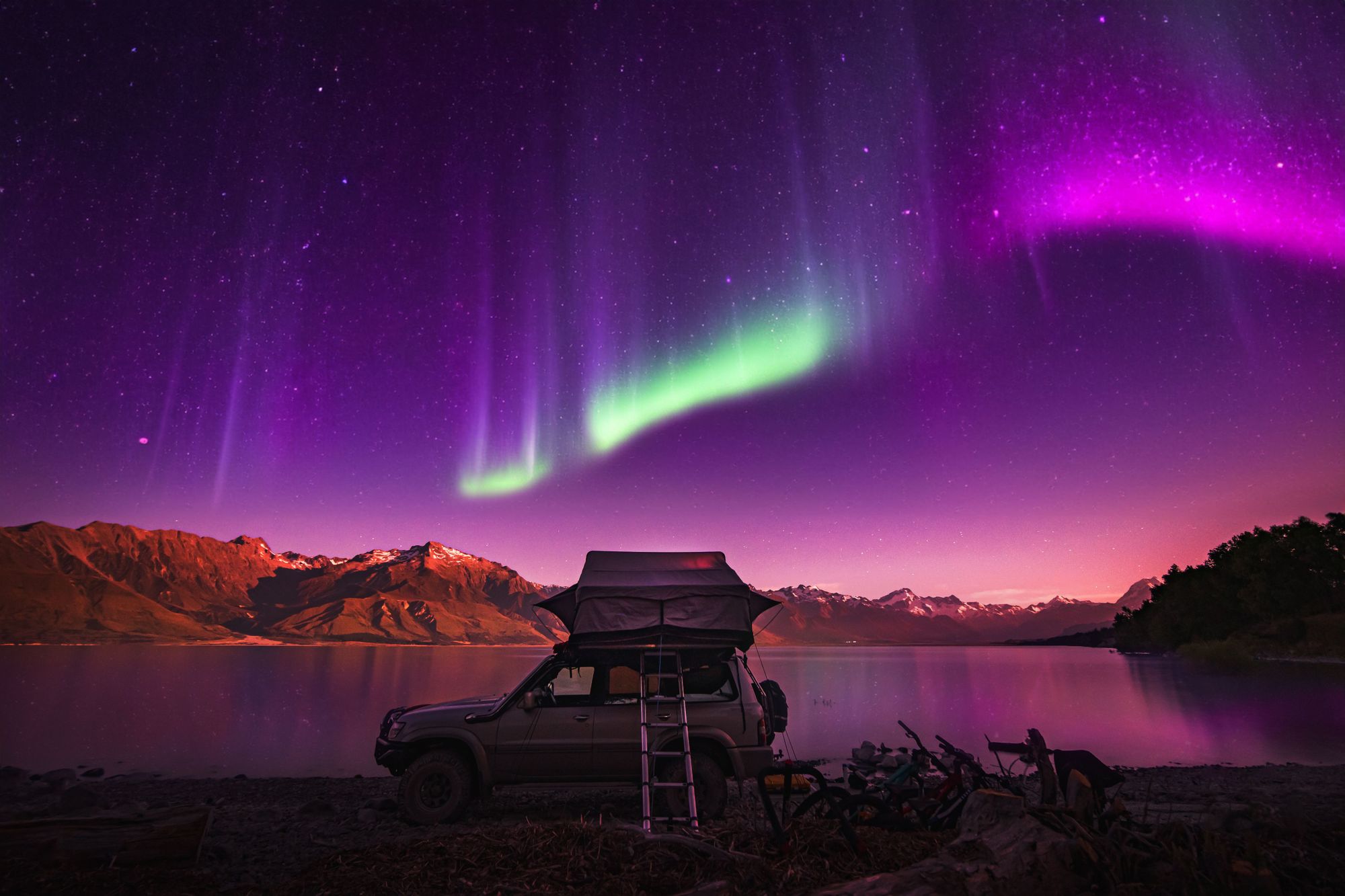 The startling pinks and greens of the aurora light up the sky, with a starry night behind. Photo: Getty