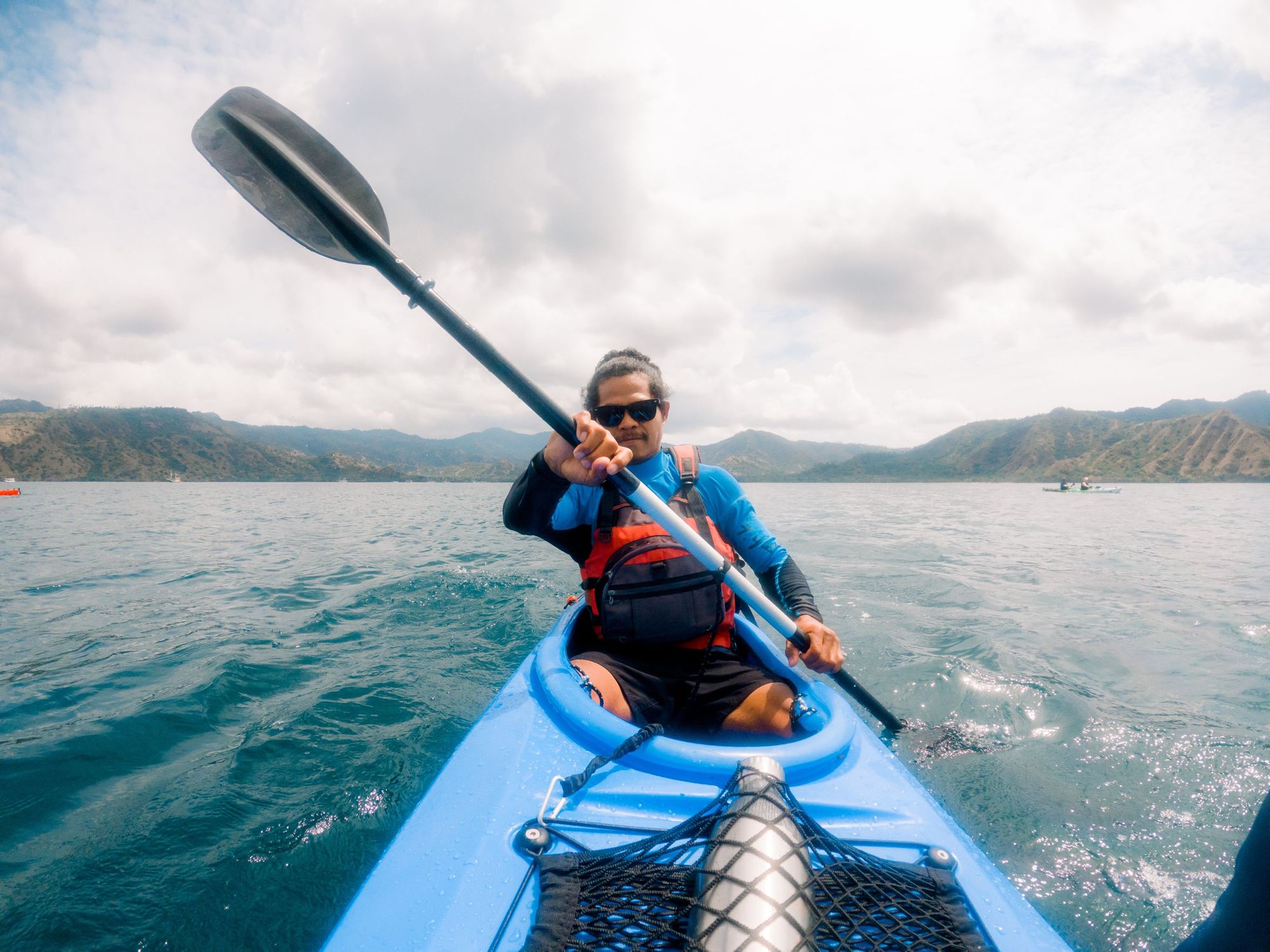 Pria Indonesia mengendarai kayak di laut, dikelilingi pulau-pulau.  Foto: Petualangan Jahat