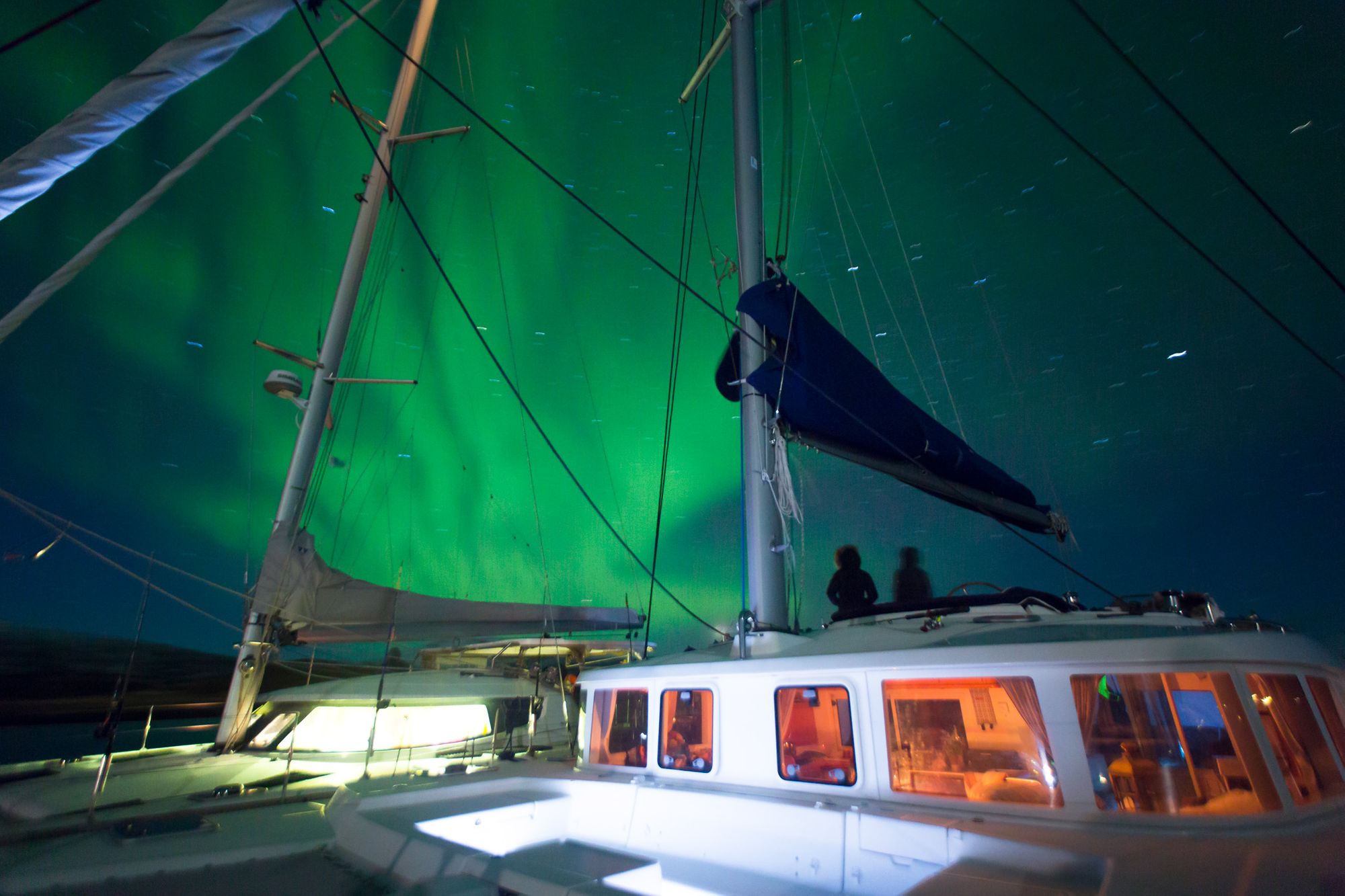 Sailing boat at night, with the northern lights behind it.