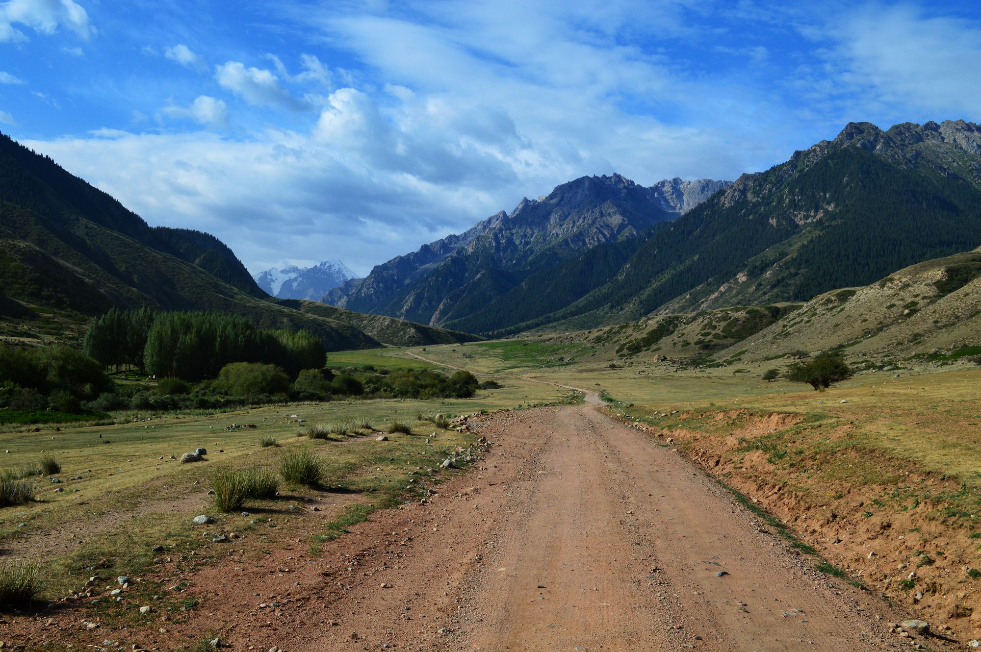 A dirt road in Kyrgyzstan, with expansive mountain views.