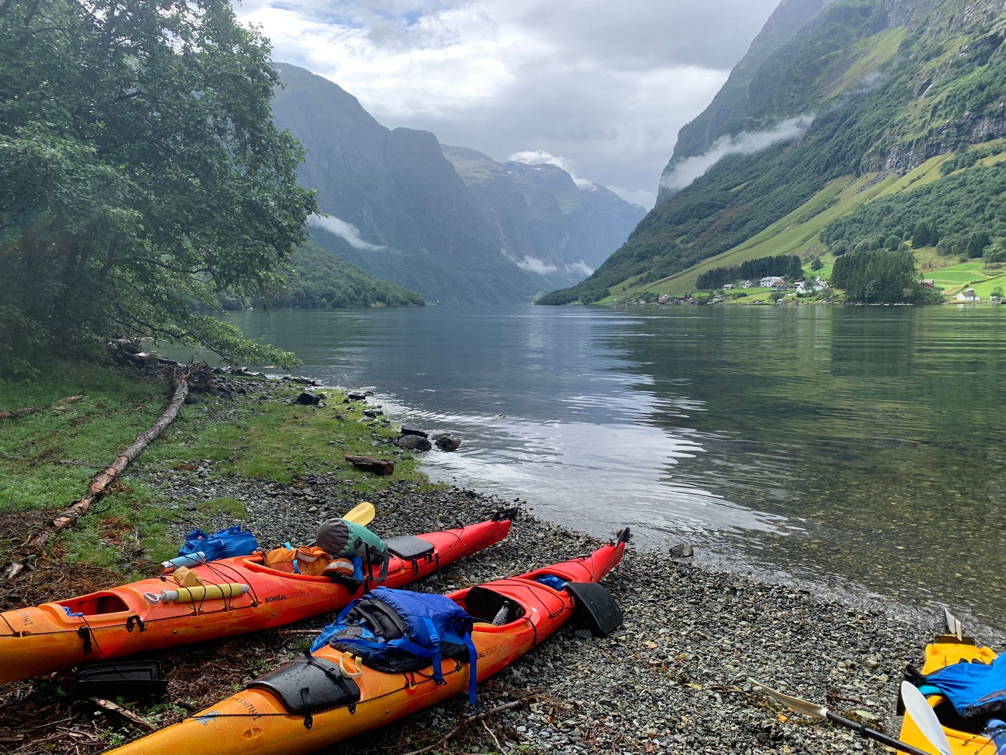 Kayaks pulled up on to the shore of the fjord in Norway.