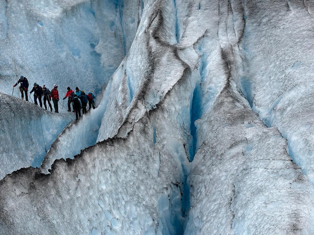 Hikers crossing the deep crevices of the Nigardsbreen Glacier, Norway.