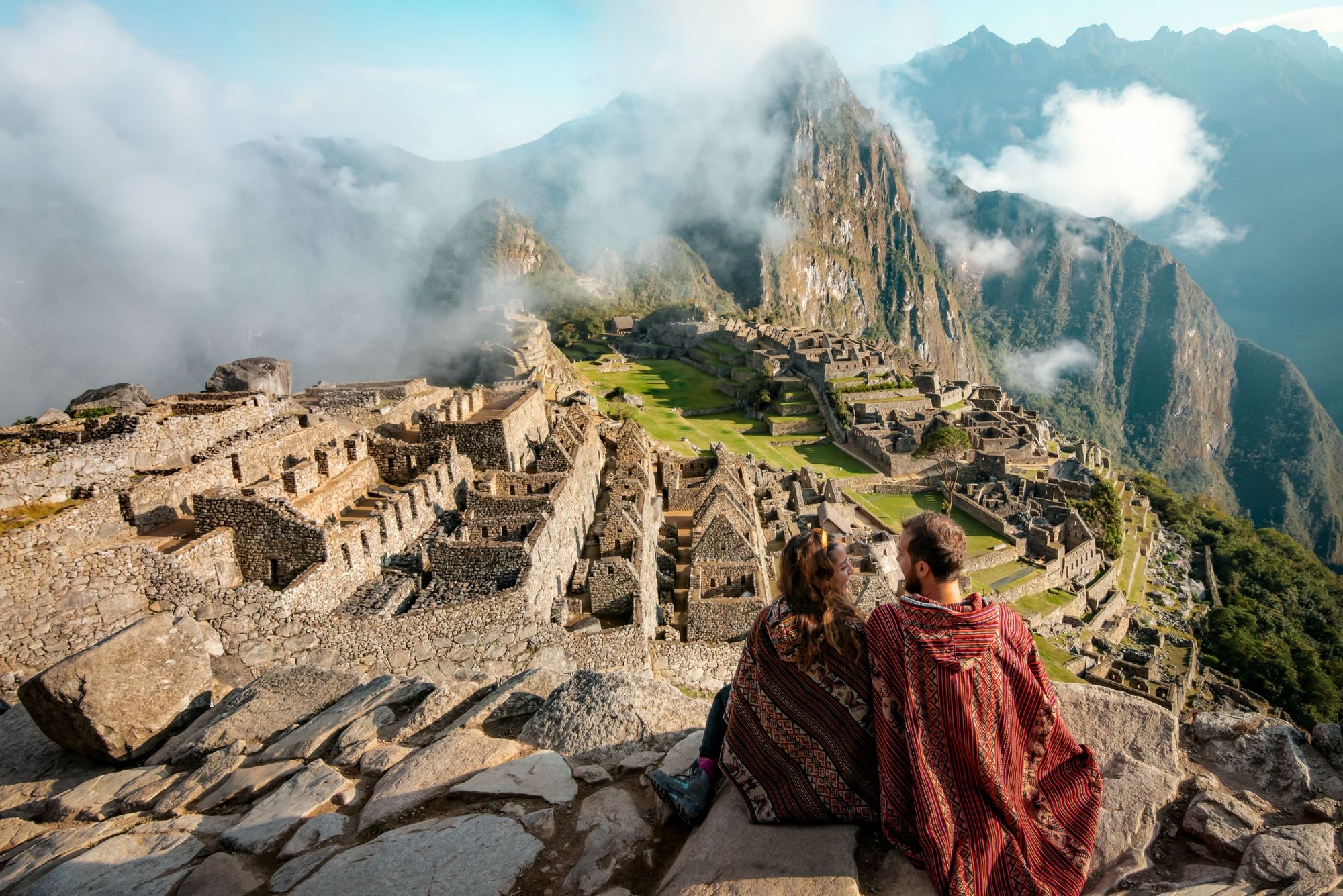 Machu Picchu in all its glory, with clouds drifting over the mountains behind.