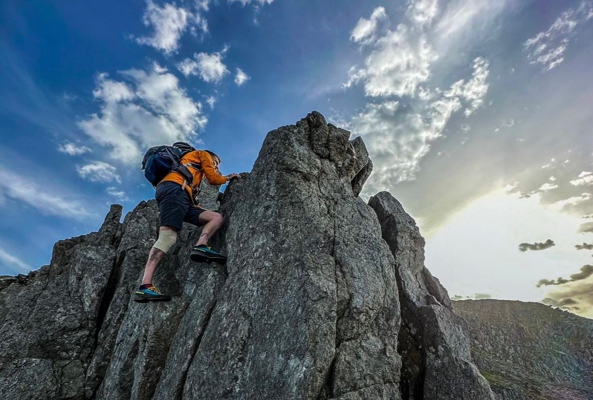 A man climbs a gritstone crag.