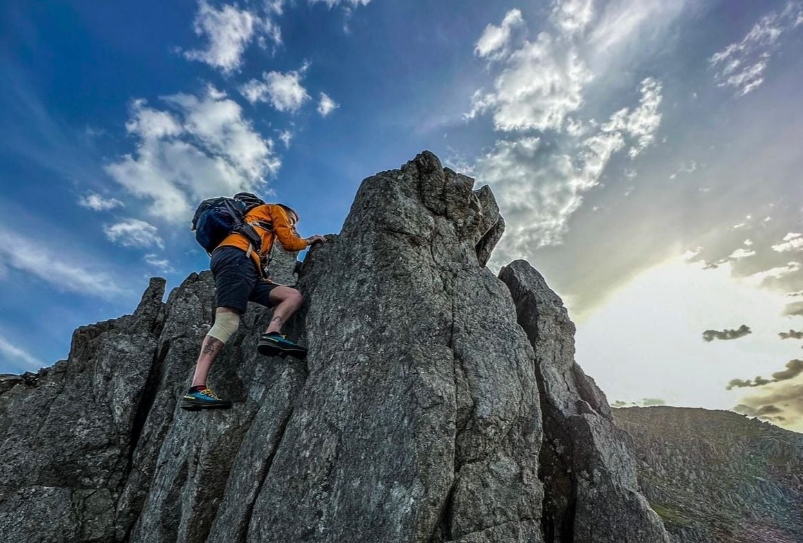 A man climbs a gritstone crag.