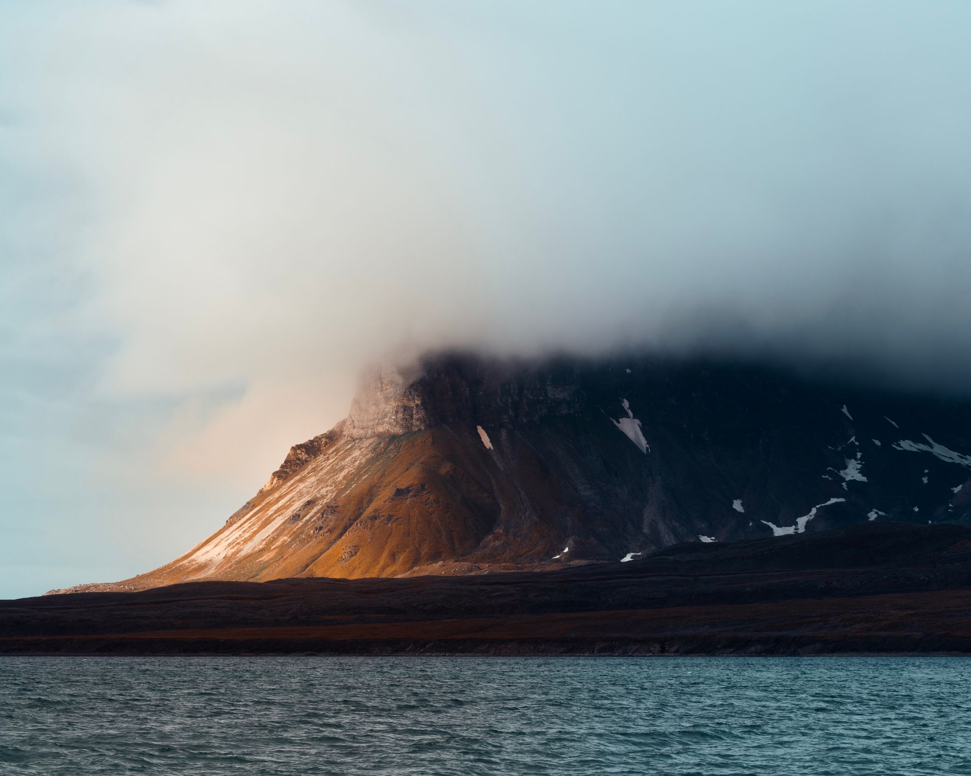 Bright sun and dramatic clouds on a mountain in Svalbard.