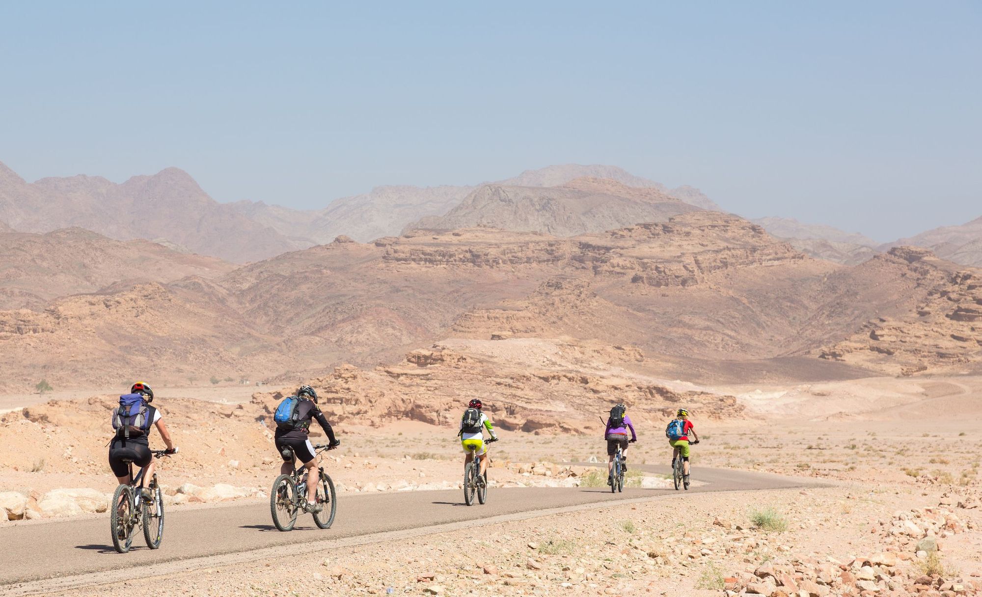 A group of cyclists ride along the road into the mountains near Aqaba, Jordan. Photo: Getty.
