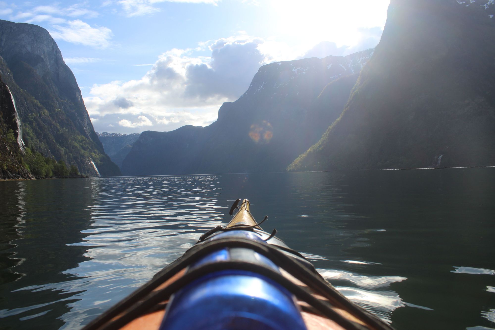 The nose of a kayak points down the fjord, on a sunny day in Norway. Photo: Stuart Kenny