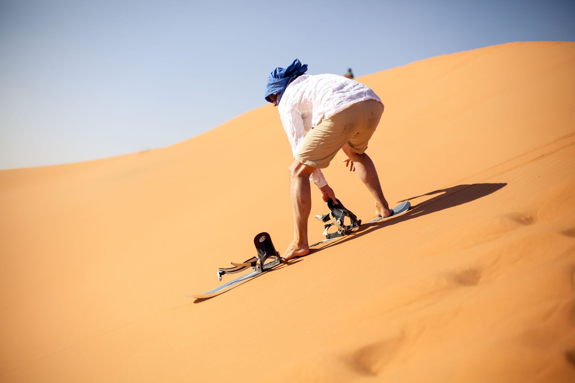 A man prepares to go sandboarding in the Sahara Desert of Morocco. Photo: Canva.