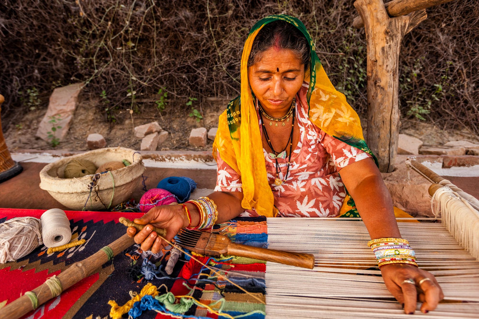 A woman weaving durries, a rug made from cotton or wool by tapestry technique, a slow process using separate bobbins or butterflies for each colour across the width interlocking with the adjacent coloured yarn. Photo: Getty