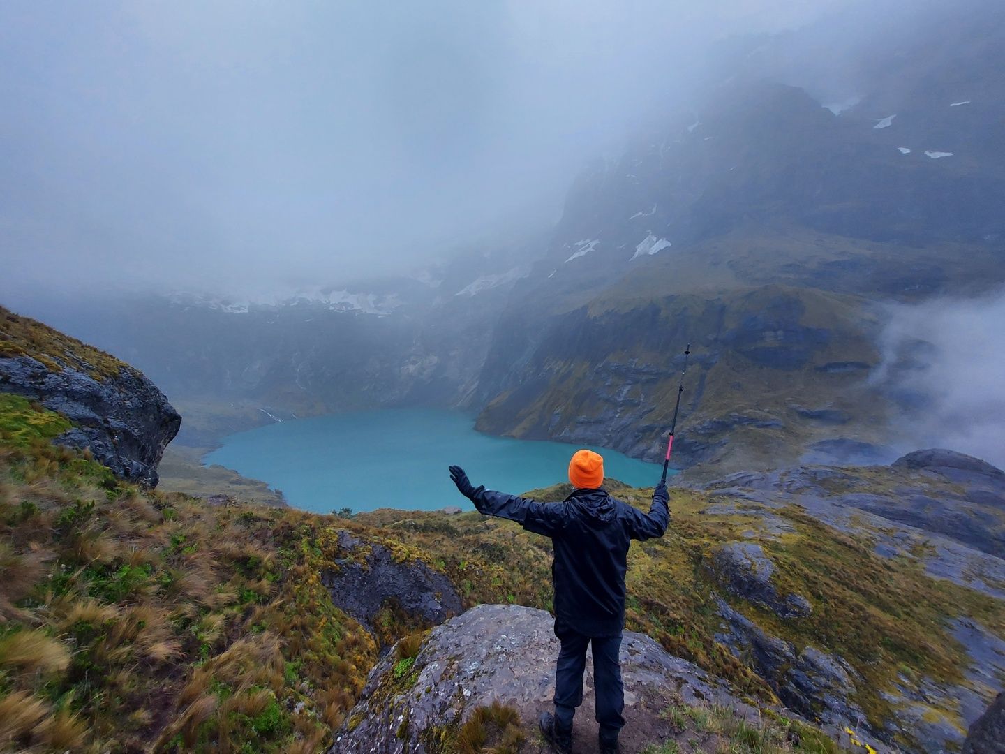 A hiker poses near Quilotoa Lake, Ecuador, in the rain.