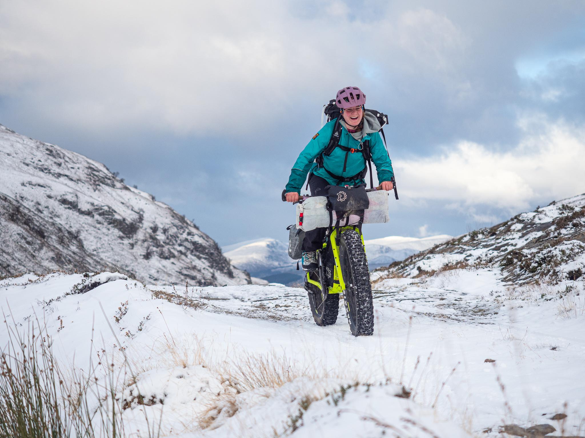 A woman fat biking in the snowy Scottish Highlands.