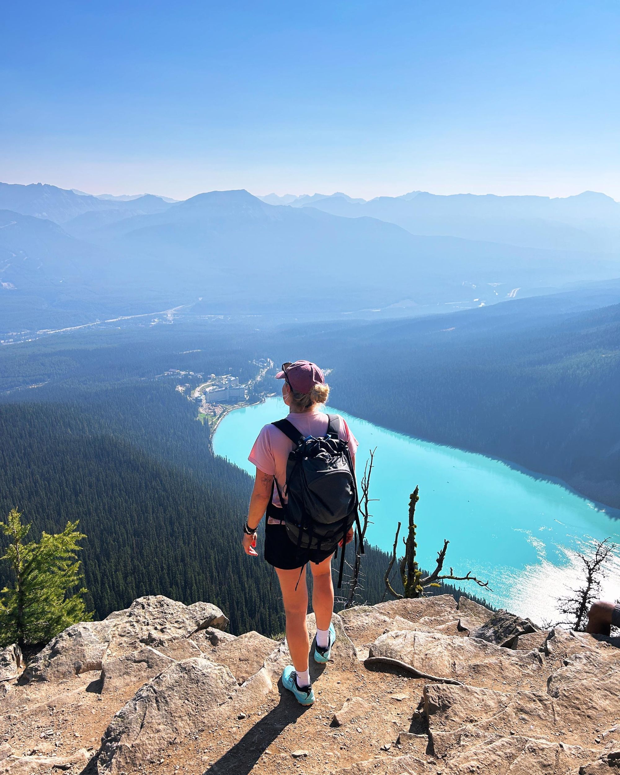 A woman looks out over the forests and lakes of a beautiful landscape.