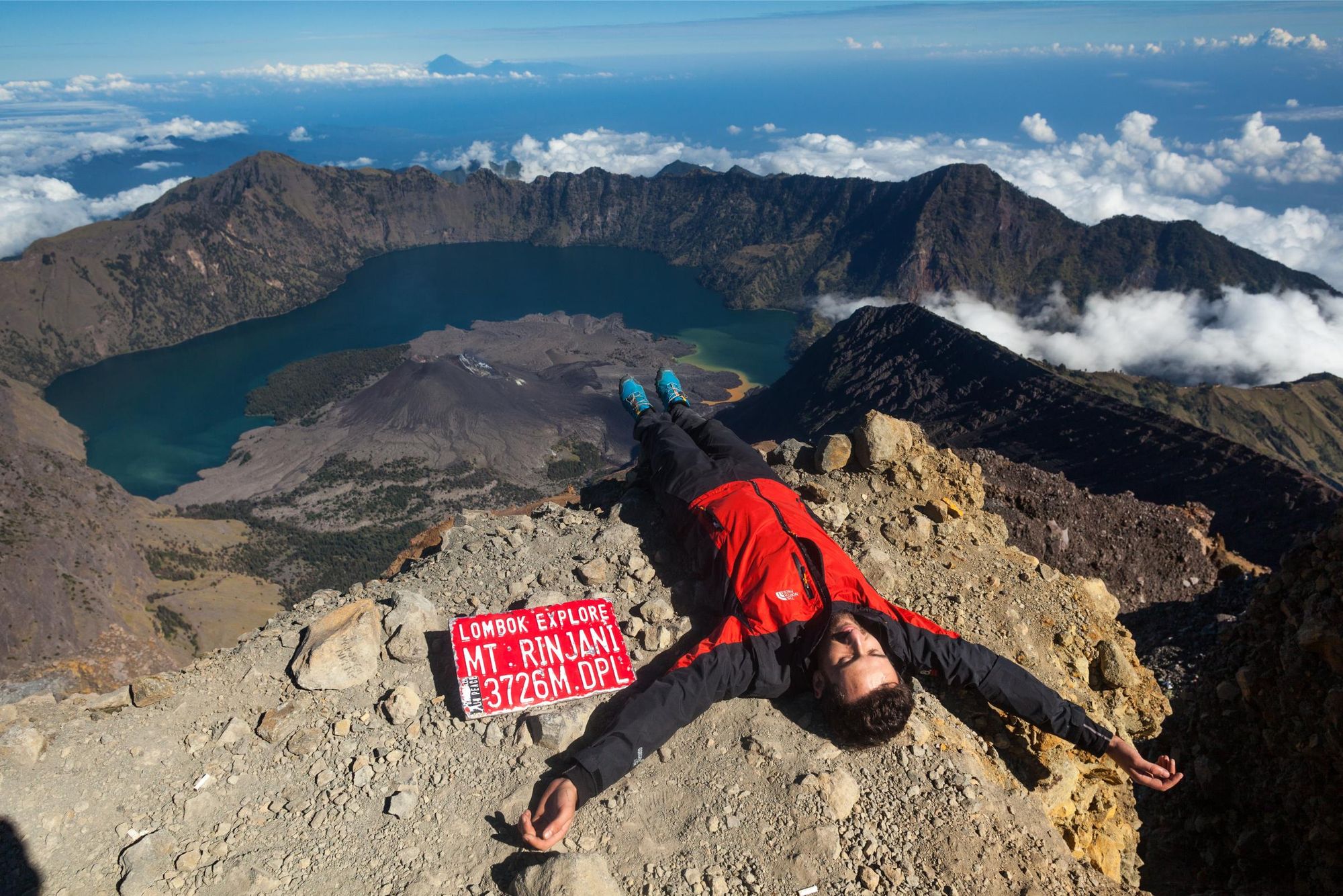 A hiker relaxes at the summit of Mount Rinjani, Lombok. Photo: Canva.