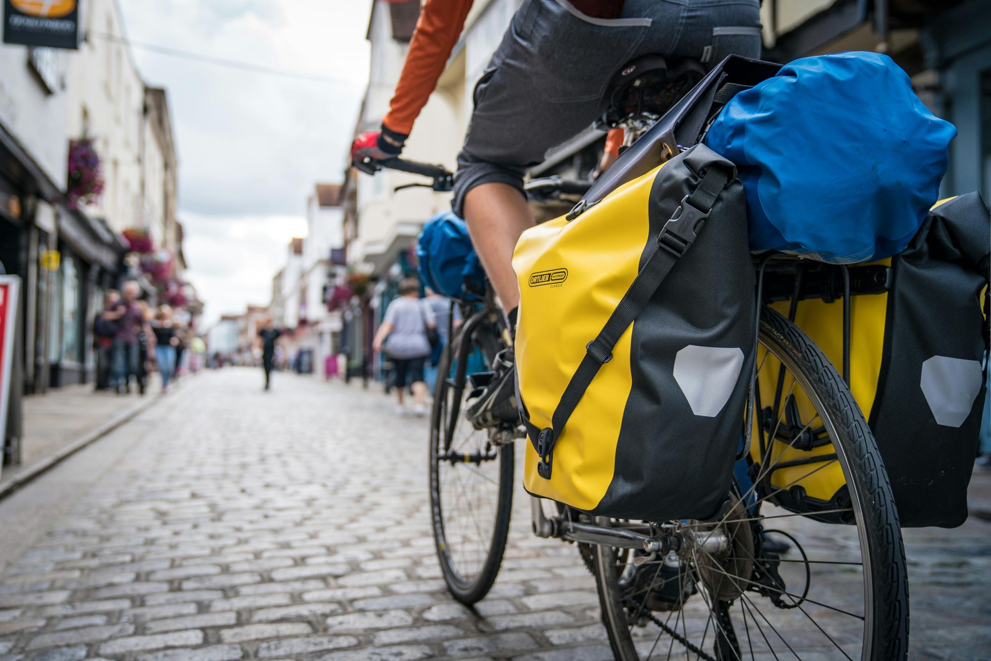 A loaded touring bike heading through a cityscape. Photo: Lucas Canino (via Unsplash)